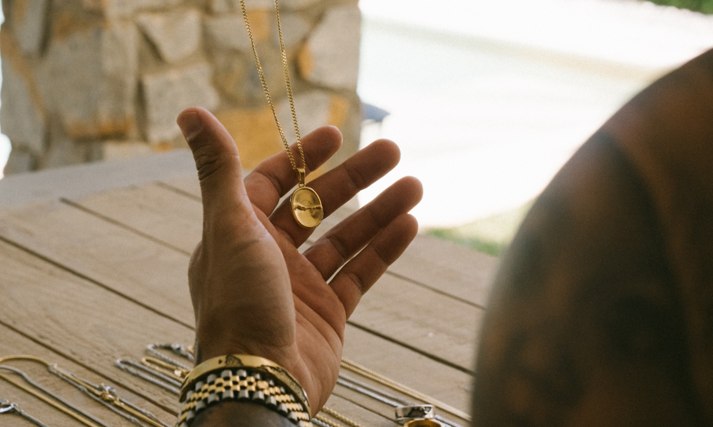 Man holding on to a pendant necklace he's been given as a gift