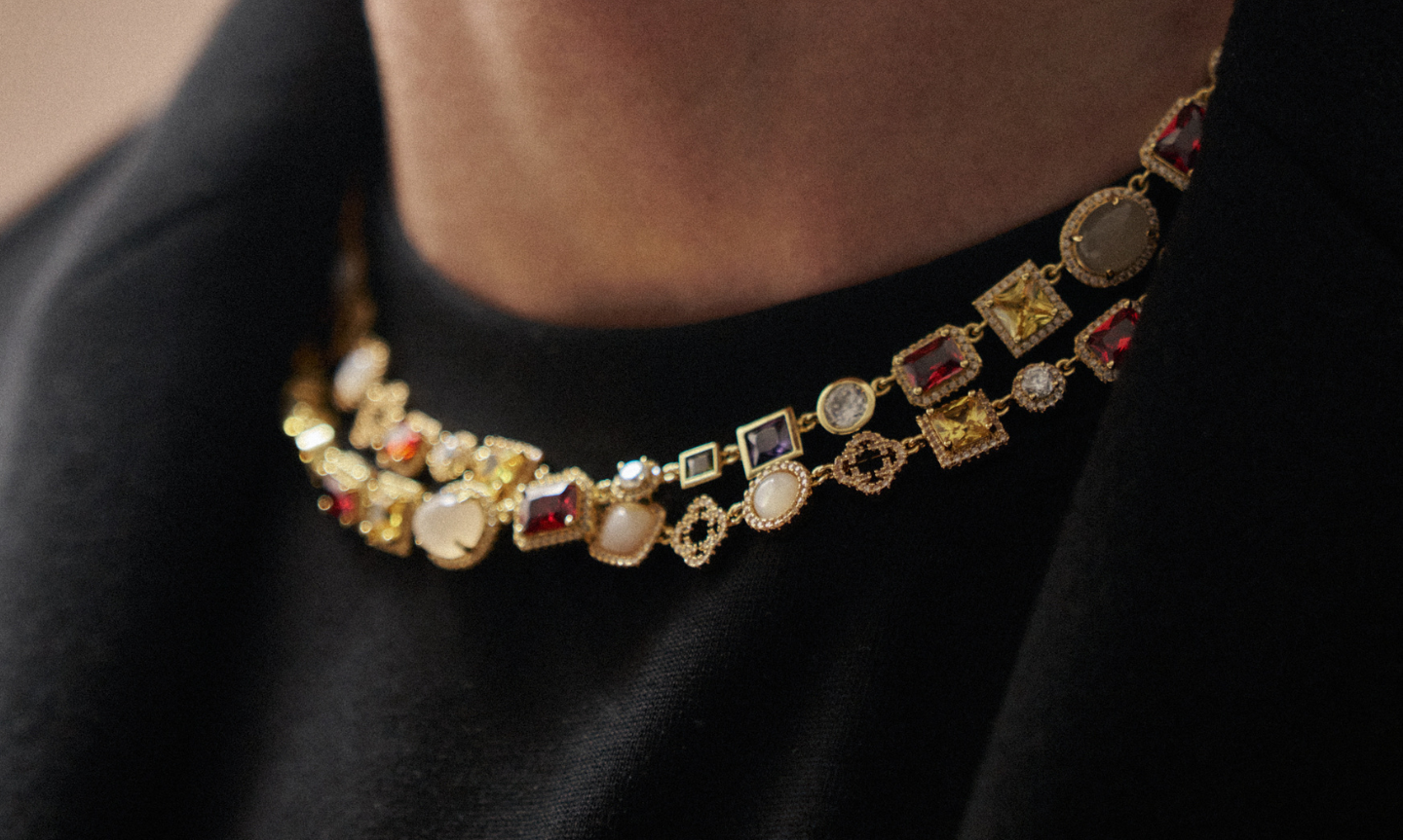 Man wearing a black winter coat and layering two 18K gold Gemstone necklaces