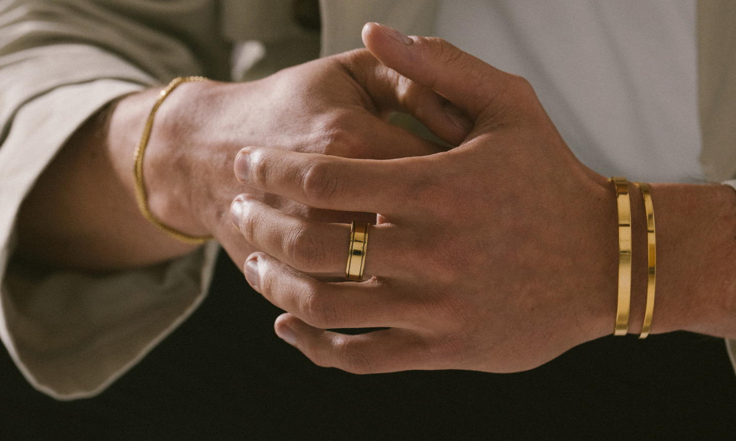 Man wearing minimalist gold jewellery gifts for men including simple bangles and rings